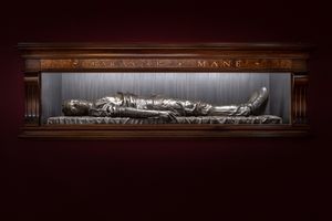 Kehinde Wiley, _The Body of the Dead Christ in the Tomb (Babacar Mané)_ (2021). Bronze and wooden frame with gold letters. 45 x 97 x 262 cm, 283 kg. Exhibition view: _An Archaeology of Silence_, de Young Museum, San Francisco (18 March–15 October 2023). ©️ 2022 Kehinde Wiley. Courtesy the artist and Templon. Photo: Ugo Carmeni.